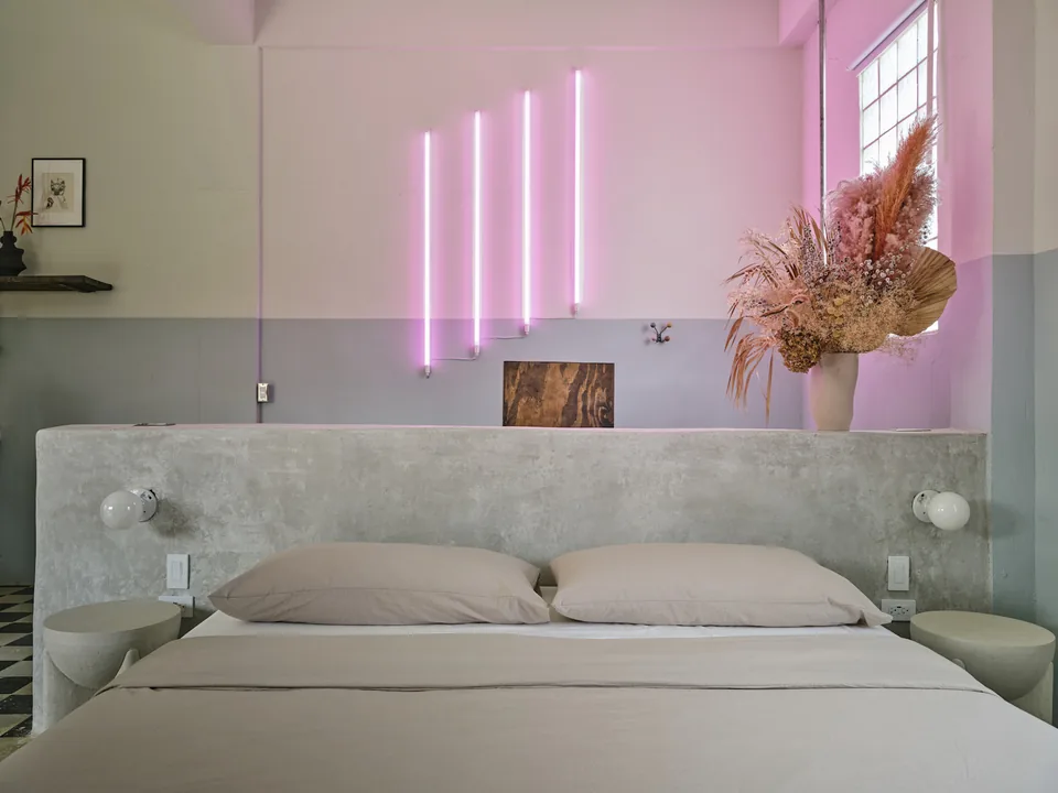 Pink neon light above the polished-concrete king bed in Verde 1