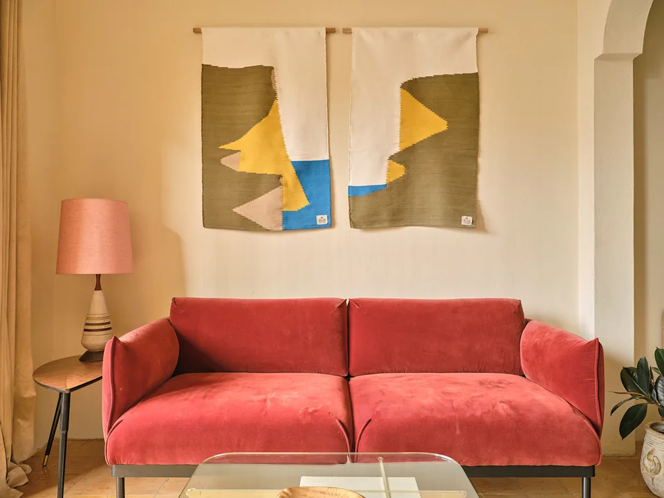 A red sofa beneath original artwork in Verde 2’s living room
