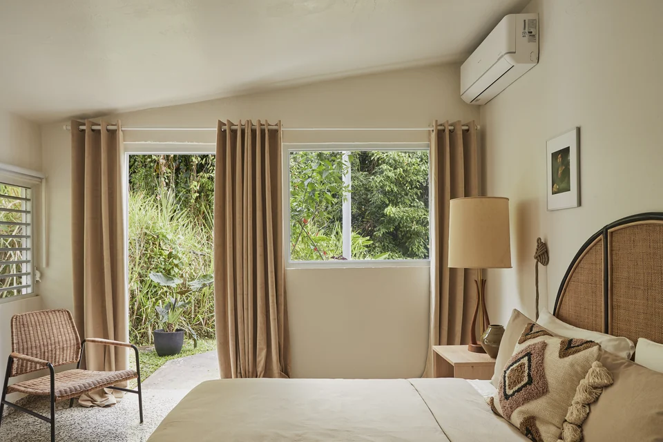 Forest-facing windows, soft curtains and a woven headboard in Wald Haus’s fourth bedroom