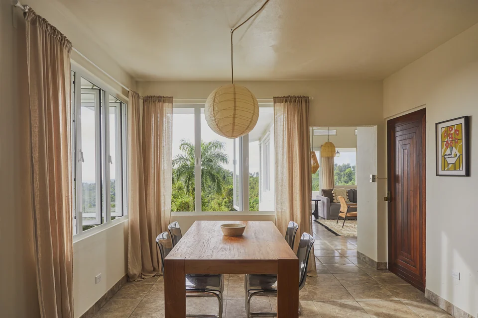 A wooden dining table and woven pendants beside Wald Haus’s wide windows