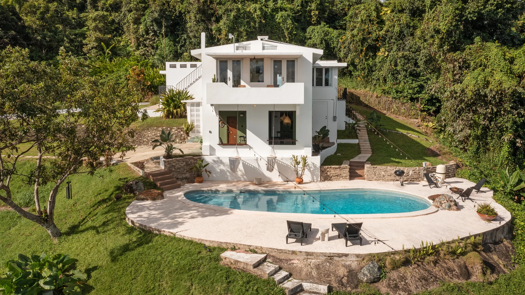 Wald Haus’s white house and curved swimming pool surrounded by rainforest