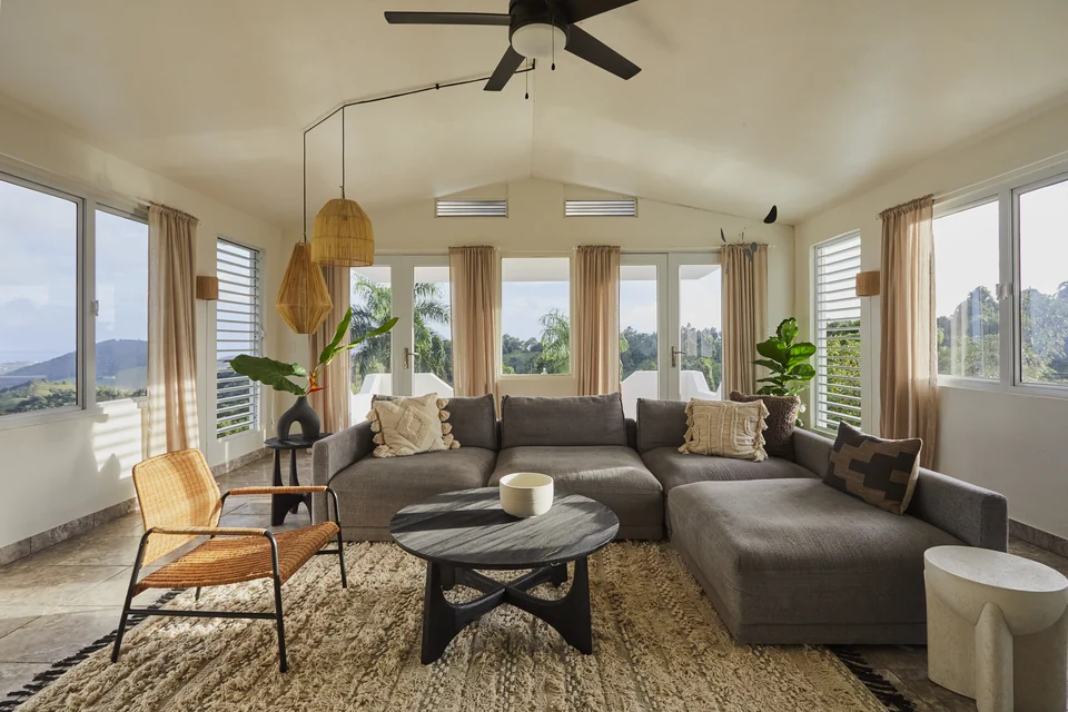 Wide windows, woven pendant lights and a gray sectional in Wald Haus’s living room