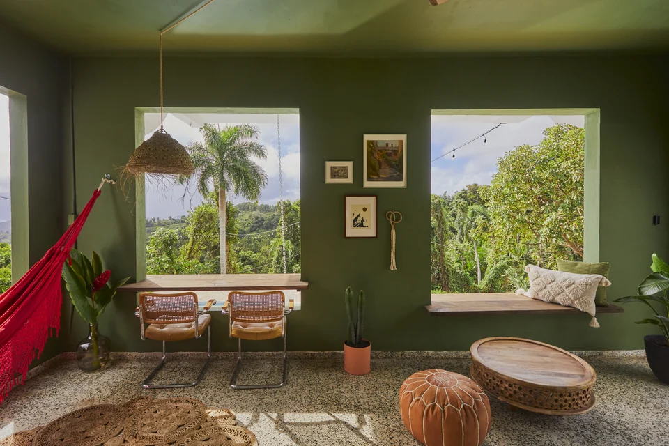 A red hammock, woven furniture and deep green walls on Wald Haus’s covered patio